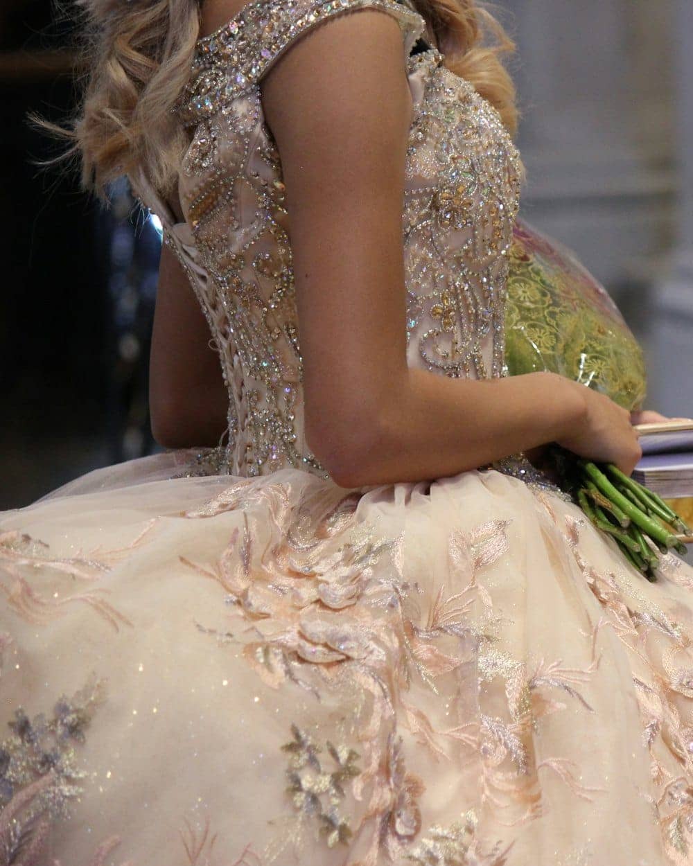 Debutante com vestido bordado segurando um buquê